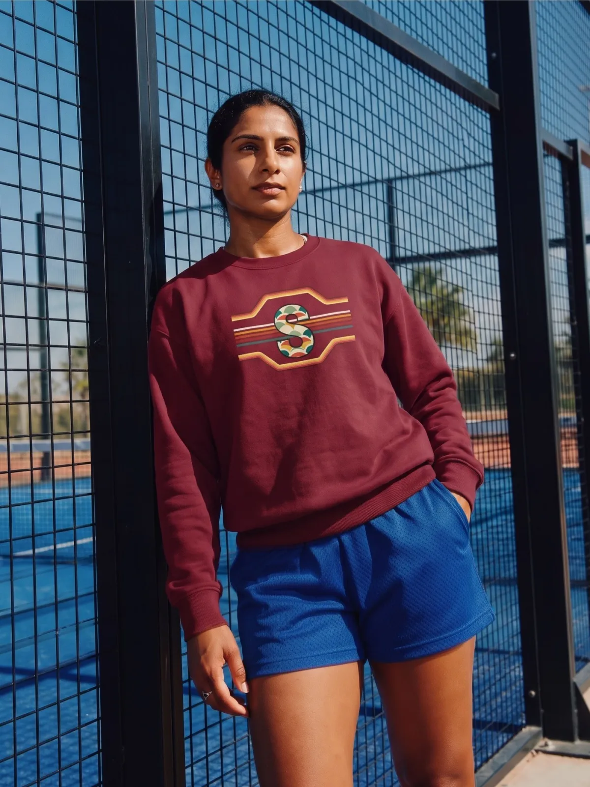 A woman in the burgundy S crewneck on a padel court