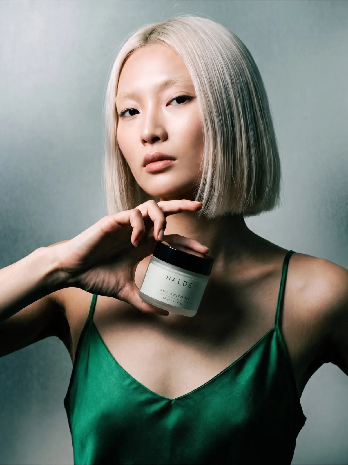 The same portrait, now holding the HALDE daily moisturiser jar